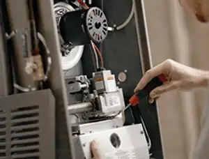 Furnace repair technician inspecting internal components and wiring in West Palm Beach, FL