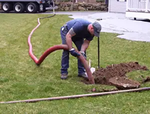 Septic pumping technician servicing a residential septic tank with a vacuum hose in West Palm Beach, FL