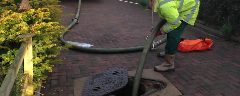 Septic tank cleaning technician servicing a septic tank with a vacuum hose in West Palm Beach, FL