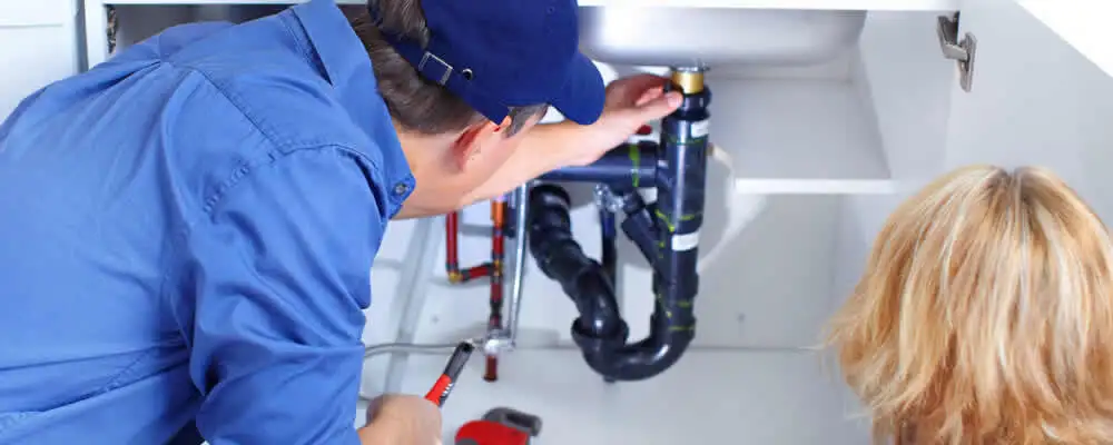 Plumber repairing under-sink drain pipes and fittings in West Palm Beach, FL